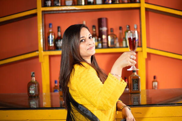 幸福的年轻印度女商人手里拿着一杯酒，企业女性庆祝公司的成功。图片下载