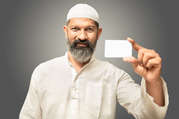 快乐的亚洲印度穆斯林男子展示空的名片或银行卡，技术推广和广告，孤立在灰色的背景上。图片下载