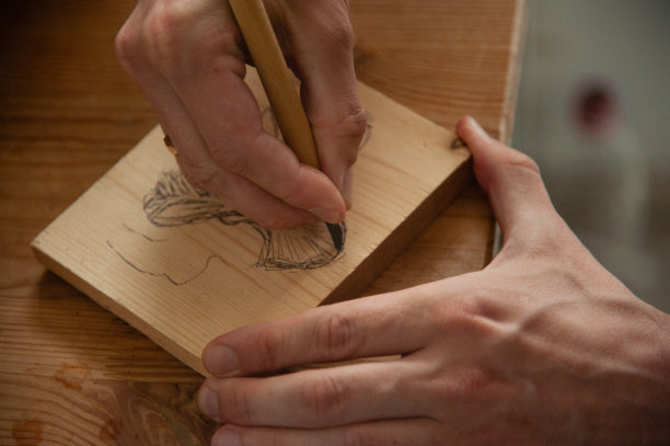 男性的手在一块木头上雕刻出动物。从上面的观点图片下载