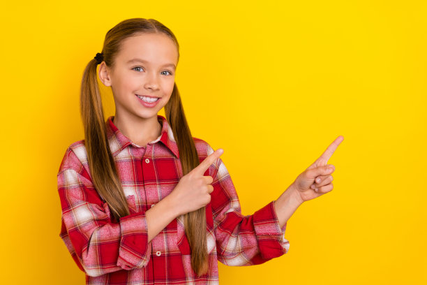可爱的学校孩子穿着格子衬衫指着空空间孤立的黄色背景照片图片下载