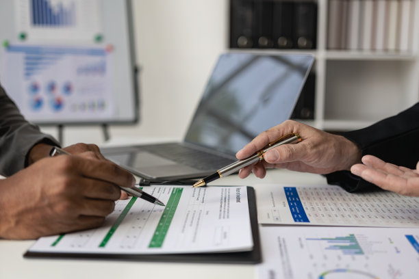 业务团队在业务演示或研讨会上会面。该文件包含财务或营销数据、图形和图表。桌子上有笔记本电脑和平板电脑。远程图片图片下载