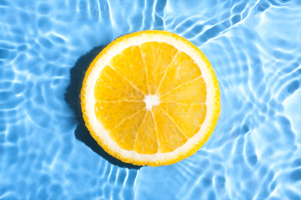 鲜橙片在水中蓝色的抽象背景。橙色切片上模糊的蓝色抽象背景。图片下载