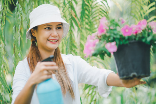 年轻女性的爱好是照顾植物，浇水，铲花。在工作休息的时候在花园里图片下载
