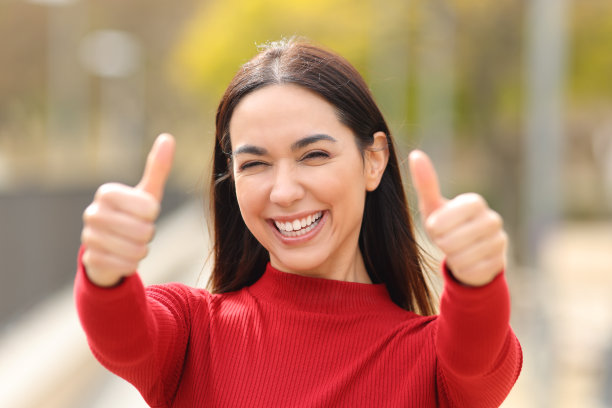 快乐的女人在公园里竖起两个大拇指图片下载