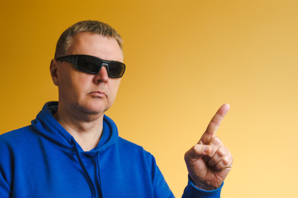 一个穿着蓝色帽衫戴着墨镜的男人的肖像。欧洲人用手指着图片下载