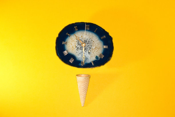 冰淇淋蛋筒与一个古老的复古时钟球在黄色的背景，创造性的夏季概念，是时候夏天的魔法图片下载