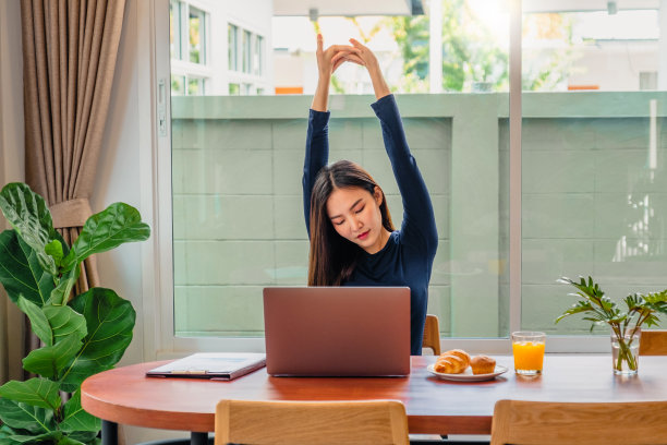 快乐的年轻女子放松的笔记本电脑和食物。在家工作。图片下载
