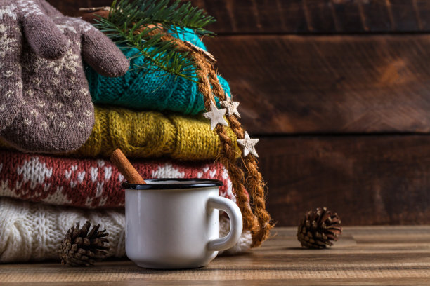 冬天，编织、折叠的毛衣，暖和的连指手套和一杯木底肉桂热可可。冬天和秋天的衣服。丑陋的圣诞毛衣图片下载
