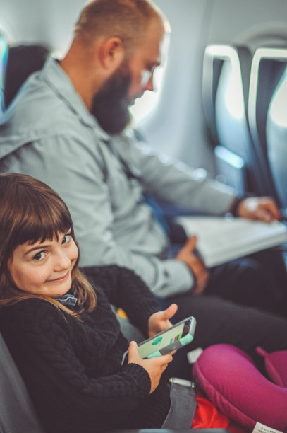和家人一起旅行的孩子在飞机上用手机玩游戏图片下载