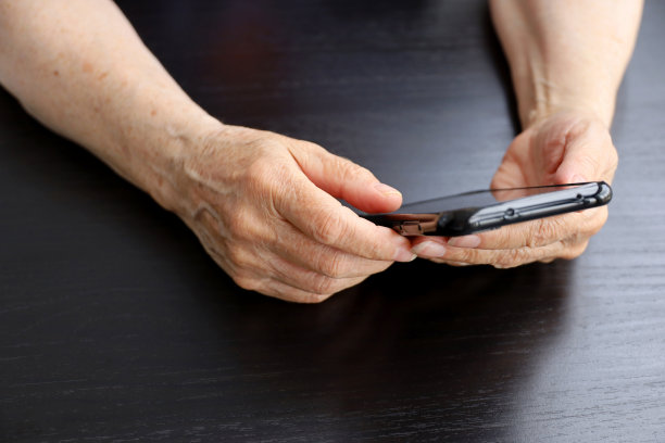 老年妇女拿着智能手机，把手机放在布满皱纹的女性手中凑近图片下载