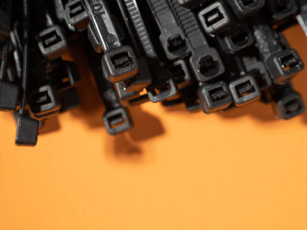 橙色背景上的黑色塑料领带。图片下载