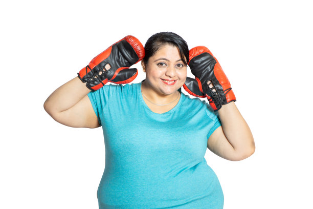 快乐的超重印度妇女戴着拳击手套看着相机孤立的白色工作室背景，减肥活动和运动的概念。图片下载
