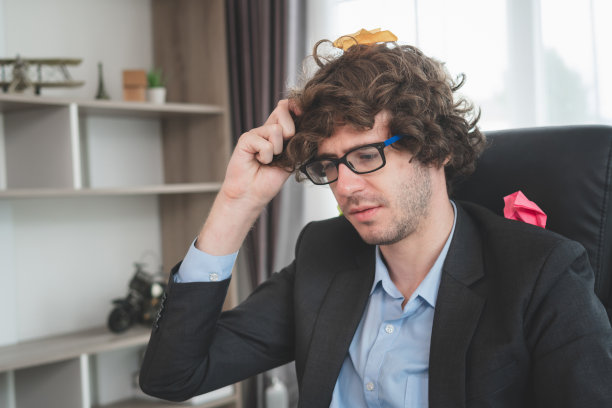 严肃忙碌的商务男士坐在办公桌旁，男士戴着眼镜在家办公图片下载