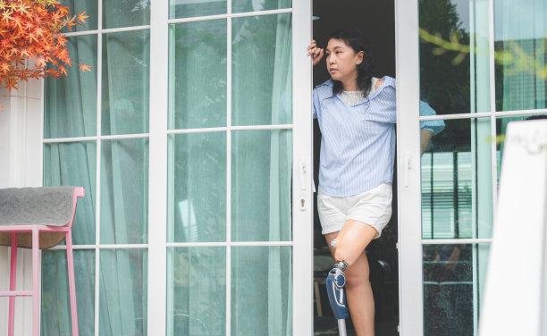 装有假腿的残疾妇女打开门，看向别处，站在家里天井门边的妇女图片下载