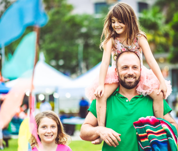 父亲带着两个孩子在户外的夏日狂欢节集市或游乐园，阖家欢乐图片下载
