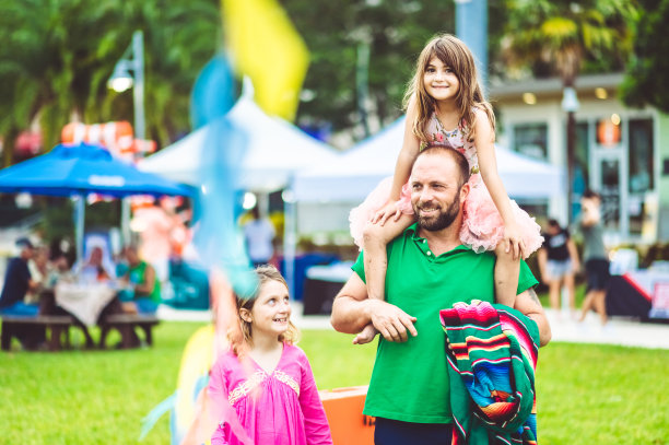父亲带着两个孩子在户外的夏日狂欢节集市或游乐园，阖家欢乐图片下载