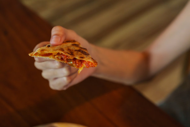 切成小块准备吃的披萨。在一个女人的手里，赶上了，准备在午餐时间吃掉图片下载