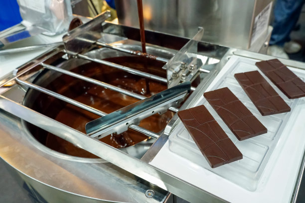 制作黑巧克力棒的过程由搅拌机进行，融化后的黑巧克力流入不锈钢碗中。图片下载