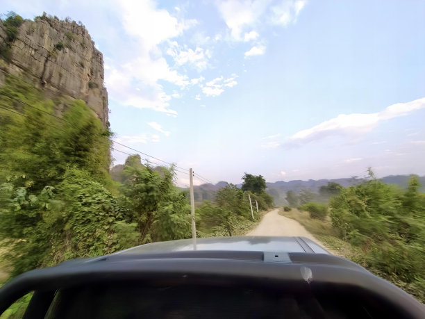 一辆汽车在山附近的土路上行驶的照片，一辆汽车在土路上行驶的景象。图片下载