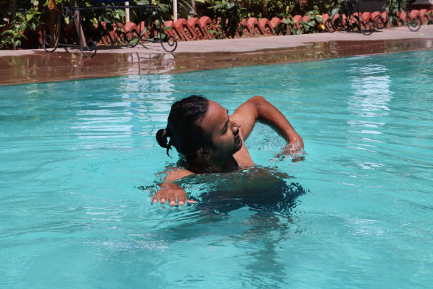 印度男子在清澈的水中做前爬的特写，室外，游泳池，绿松石蓝色马赛克瓷砖被波纹水扭曲，游泳和飞溅，波涛汹涌的水面反射，重点放在前景图片下载