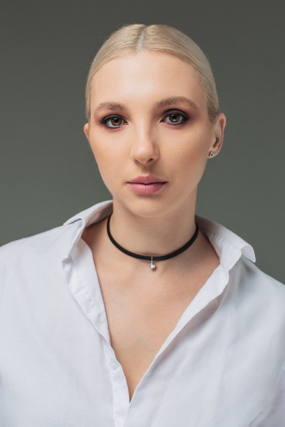 演播室里穿着灰色背景白衬衫的金发女商人。肖像图片下载