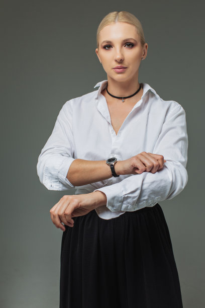 演播室里穿着灰色背景白衬衫的金发女商人。肖像图片下载