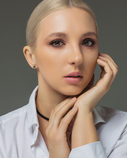 演播室里穿着灰色背景白衬衫的金发女商人。肖像图片下载