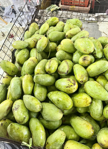 一张桌子上一篮子青芒果的照片，桌子上篮子里的青芒果。图片下载