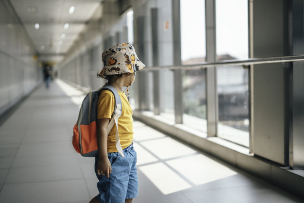 学龄前学生背着帆布背包走在城市的人行天桥上图片下载