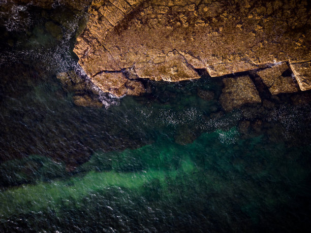 从空中俯瞰大海，沿着葡萄牙海岸的岩石形成纹理和形状图片下载