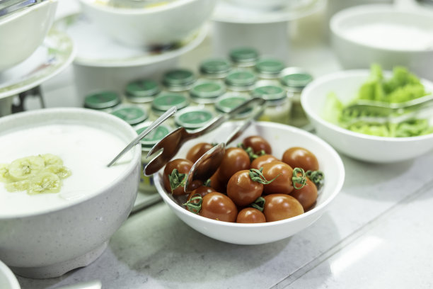 鸡尾酒番茄放在自助餐桌上的碗里，旁边是酸奶和生菜。图片下载