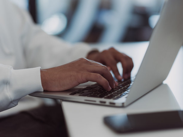 在现代办公环境中，一位非洲裔美国商人正在他的笔记本电脑上勤奋地工作，在他的专业环境中体现了决心、雄心和生产力图片下载