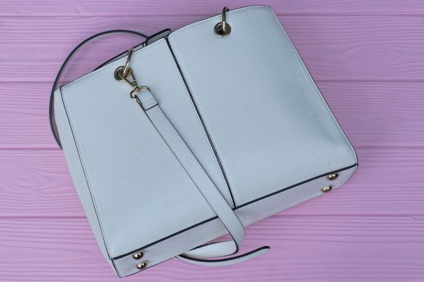 粉红色的木桌上放着一个白色的大皮包图片下载