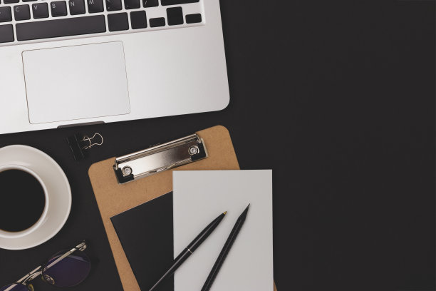 文具，笔记本电脑和一杯咖啡在黑色的背景。图片下载