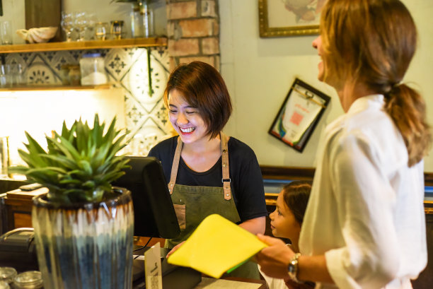 年轻的越南女服务员在咖啡厅与顾客一起结账图片下载