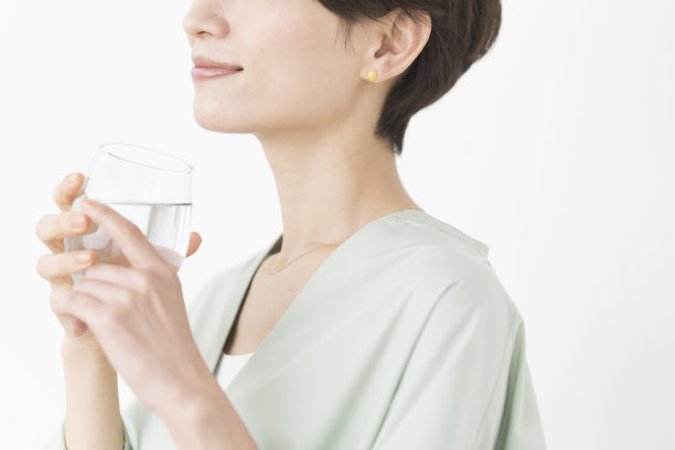 一位亚洲妇女正在喝一杯水。图片下载