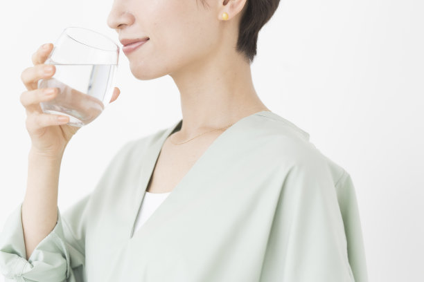 一位亚洲妇女正在喝一杯水。图片下载