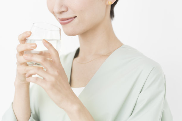 一位亚洲妇女正在喝一杯水。图片下载