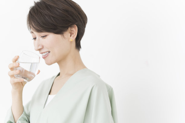 一位亚洲妇女正在喝一杯水。图片下载