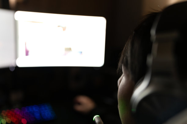 亚洲男性戴着耳机在网上玩电脑视频游戏。图片下载