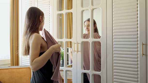 优雅的女人在卧室里挑选早晨穿的衣服。服装选择的概念，时尚和风格。图片下载