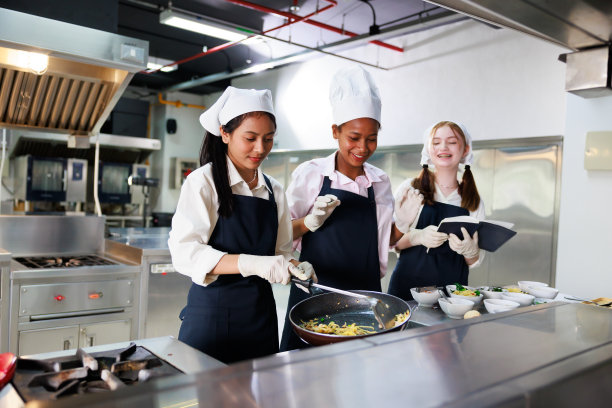 记在本子上。烹饪课。烹饪教室。一群快乐的多民族女学生正在烹饪学校学习烹饪课程。图片下载