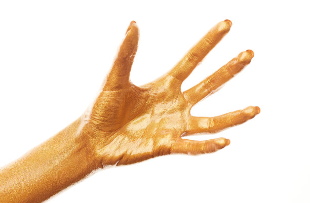 双手涂上金色的颜料。金手指。女性的手被孤立在白色背景上。白人女性放松的手显示符号和手势。图片下载