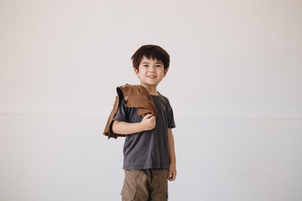 一个男孩的肖像，穿着灰色衬衫，肩上披着斗篷，面带微笑。图片下载