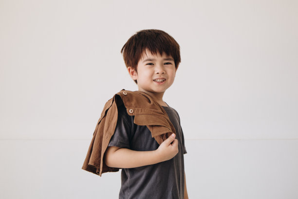 一个男孩的肖像，穿着灰色衬衫，肩上披着斗篷，面带微笑。图片下载