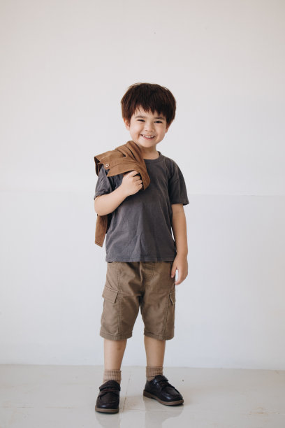 一个男孩的肖像，穿着灰色衬衫，肩上披着斗篷，面带微笑。图片下载