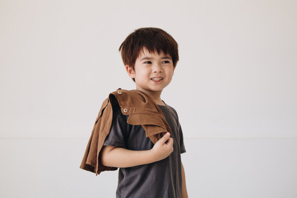 一个男孩的肖像，穿着灰色衬衫，肩上披着斗篷，面带微笑。图片下载