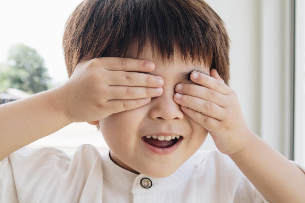 一个可爱的男孩用双手遮住眼睛。图片下载