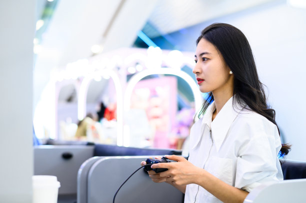 亚洲年轻女子用游戏控制器玩电子游戏图片下载