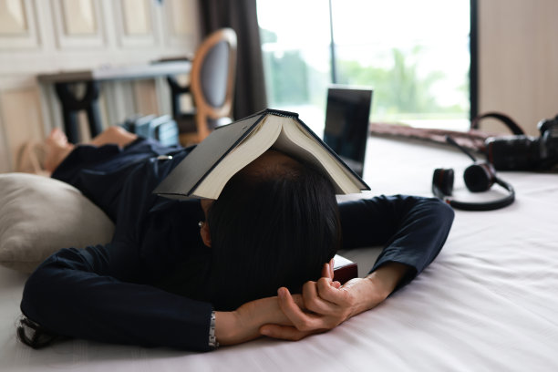 商务女性努力工作，在酒店远程工作期间睡在床上，累了的商务睡在床上图片下载